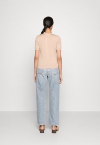 Top beige de manga corta con escote redondo, combinado con jeans rectos de tiro alto de color azul claro, con dobladillos deshilachados y bolsillos traseros.