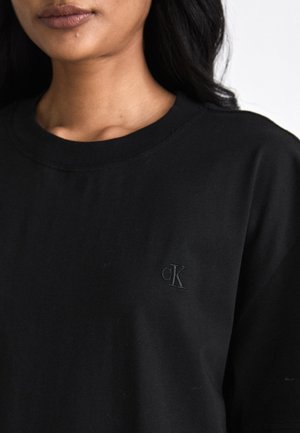 Zwarte katoenen t-shirt met een ronde hals, voorzien van een klein, reliëf CK-logo op de linkerkant van de borst. Zachte textuur, casual pasvorm.