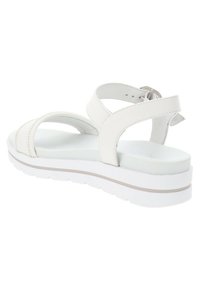 White sandal featuring a smooth faux leather upper, adjustable ankle strap, and a thick white sole with a subtle beige accent.