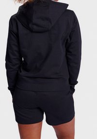 Sudadera negra con capucha y pantalones cortos a juego, con una textura suave y un corte relajado. Sin patrones ni logotipos visibles.