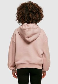Lichtroze hoodie met een ontspannen pasvorm, grote capuchon en geribde manchetten. Gemaakt van zachte stof, met een gladde textuur en een minimalistisch ontwerp.