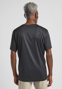 Zwarte atletische t-shirt met korte mouwen, gemaakt van gladde, vochtafvoerende stof. Heeft een ronde halslijn en een ontspannen pasvorm, met minimale details.
