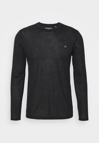 Black long-sleeve shirt made of a lightweight, textured fabric. Features a crew neckline and subtle "ck" logo on the upper left chest.
