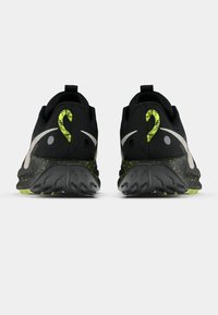 Crne sportske tenisice s teksturiranim gornjim dijelom, neonsko zelenim detaljima, karakterističnim dizajnom pete i čvrstim gumenim potplatom s uzorcima za prianjanje.