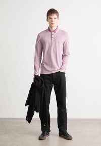 Svijetloplavi majica s dugim rukavima i ovratnikom s tri gumba, u kombinaciji s crnim hlačama i crnim sakoom. Ležerna obuća.