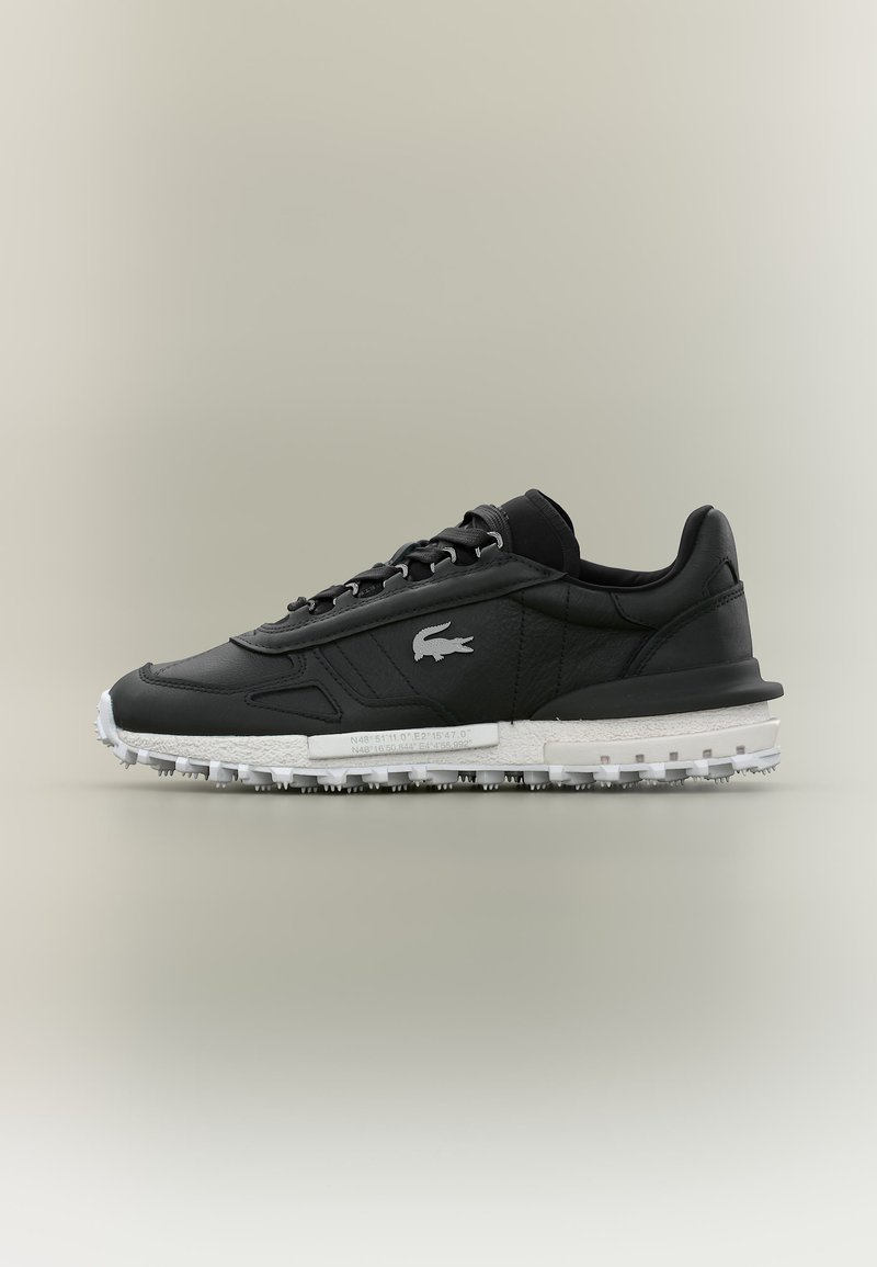 Μαύρο sneaker χαμηλού τύπου με λευκή υφασμάτινη σόλα, κορδόνια και μικρό λογότυπο κροκοδείλου στο πλάι, εμφανίζεται σε ουδέτερο φόντο.