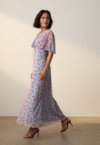 Maxikleid aus leichtem Stoff mit blauem Hintergrund und pinken sowie orangefarbenen Blumenmustern, kurzen Ärmeln und weitem Rock.