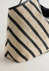 Gestreifte Tasche mit gewebtem Stoff in Beige und Schwarz, die ein lässiges Design und lederne Akzente am oberen Rand aufweist.