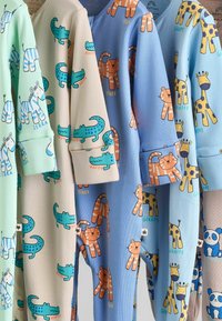 Quattro tutine per bambini dai colori vivaci presentano motivi di animali: zebra verde, coccodrillo beige, tigre blu e giraffa azzurro chiaro, con tessuto morbido al tatto.