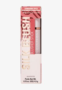 Stick de rubor en un envase blanco con acentos dorados. La caja presenta un diseño abstracto en rosa y rojo con el texto "Sundown Spice" y "Silk Blush".