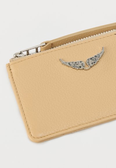 Δερμάτινη θήκη καρτών σε ανοιχτό μπεζ με υφή, με ασημένιες διακοσμήσεις φτερών και ασφαλή φερμουάρ. Συμπαγής ορθογώνιος σχεδιασμός.