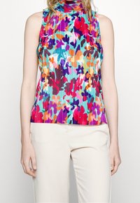 Top sin mangas de canalé en colores vivos con un cuello alto. Patrón floral en colores vibrantes sobre un fondo azul claro.