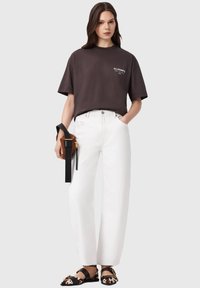 Μαύρο φαρδύ t-shirt, λευκό τζιν με φαρδιά παντελόνια, καφέ τσαντάκι χιαστί και μαύρα παπούτσια μπαλαρίνες με μοτίβο αγελάδας. Απλό, μοντέρνο ντύσιμο.