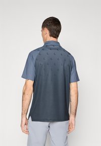 Dark blue short-sleeve polo with a gradient pattern, featuring a textured fabric and subtle logos on the back, standard collar design.
