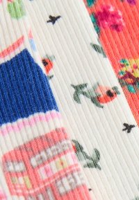 Tre coppie di calzini che mostrano vari motivi: texture a coste, righe blu e rosa, design floreali e piccoli motivi di uccelli su uno sfondo bianco.