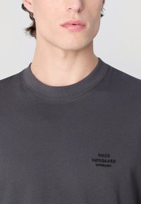 Grå bomulls t-skjorte med rund hals. Har subtil brodering "MADS NØRGAARD COPENHAGEN" på brystet. Myk tekstur, slim fit.