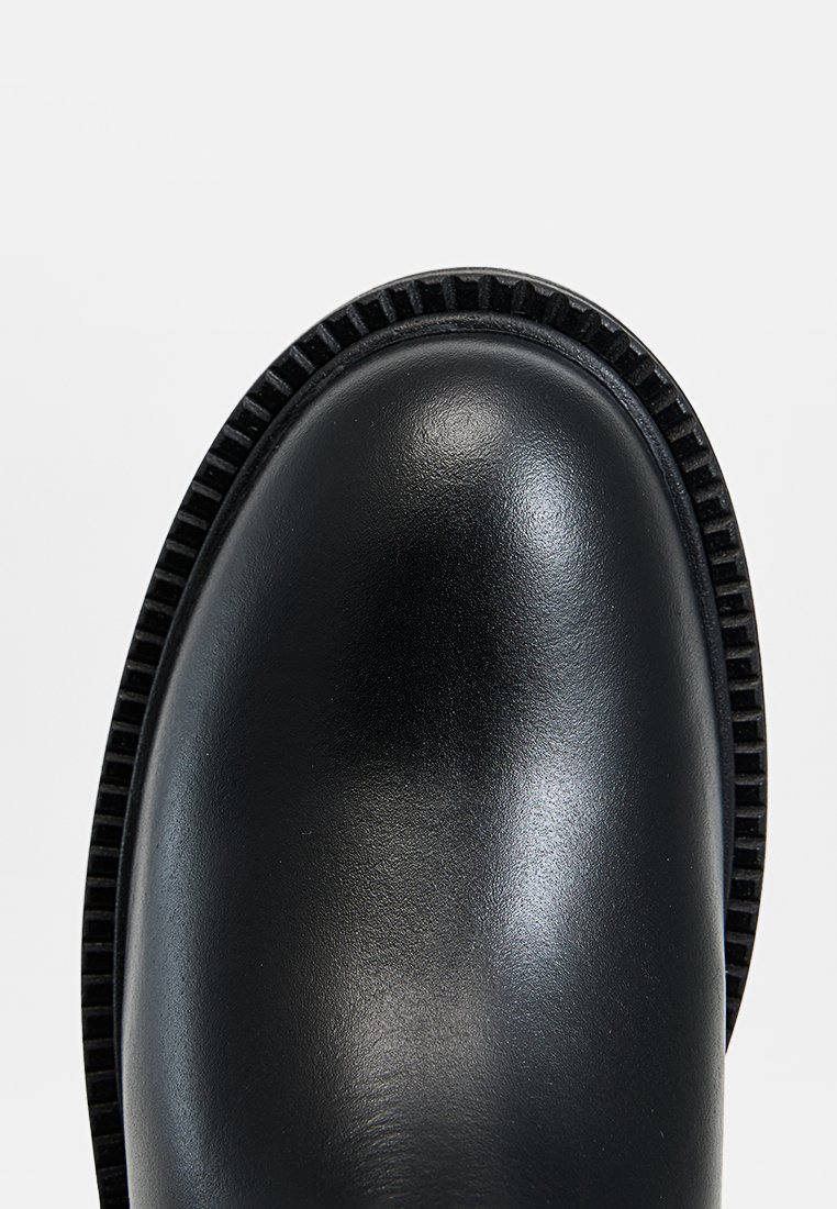 Zwarte leren enkelboot met een ronde neus, gestructureerde rand en rubberen zool. Gladde afwerking met een slank ontwerp en geen zichtbare hardware.