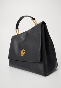 Sac à main en cuir noir au design structuré, avec un fermoir et des accessoires dorés, ainsi qu'une poignée courte et robuste.