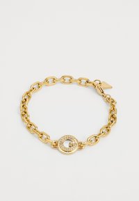Pulsera de cadena dorada con eslabones grandes y un cierre circular acentuado con gema que presenta un diseño de "G". Textura lisa con acabado brillante.