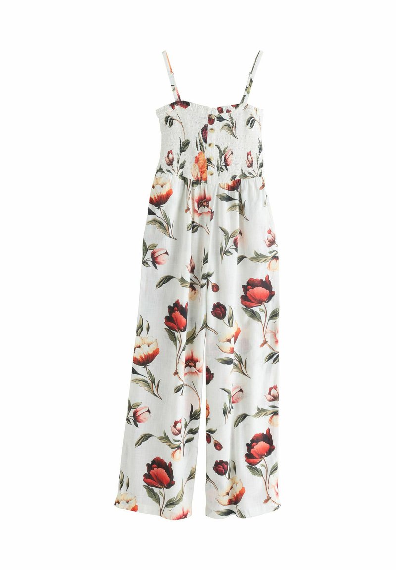 Combinaison blanche sans manches avec imprimé floral rouge et rose, corsage smocké, détails à boutons et pantalons à jambes larges.