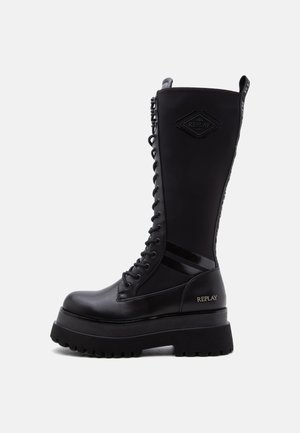 Botte noire à lacets montant jusqu'au genou, avec une semelle épaisse, une semelle extérieure en caoutchouc et le logo "Replay" sur le côté et la partie supérieure de la tige.
