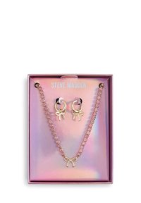 Ensemble collier et boucles d'oreilles en ton or avec des rhinestones roses et des accents de nœud, présenté dans un emballage rose brillant avec le nom de la marque.