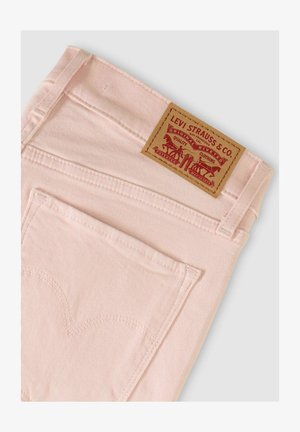 Lyserøde denimjeans med en baglomme, der har karakteristisk hjerteformet syning, og et brunt lædermærke med grafiske detaljer.