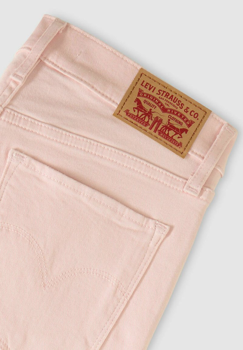 Jean en denim rose avec une poche arrière ornée d'une couture en forme de cœur distinctive et une étiquette de marque en cuir marron clair avec des détails graphiques.