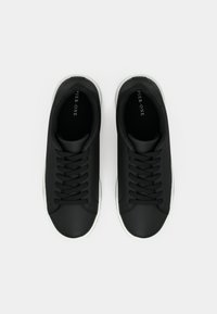 Mustad must sneakers, mille siled, mati viimistlusega, valge kummine talla ja mustade paeltega, kaubamärgi nimi on peenelt joonistatud sisse.