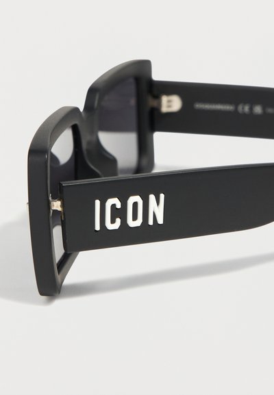 Μαύρα ορθογώνια γυαλιά ηλίου με παχιά πλαίσια και τη λέξη «ICON» σε λευκό στο πλαϊνό μέρος του σκελετού.