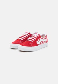 Baskets en daim rouge avec lacets blancs et motifs à carreaux, dotées d'une semelle en caoutchouc blanche et de détails de couture contrastés.