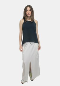 Top in cotone color navy abbinato a una gonna maxi bianca con tasche laterali, uno spacco e una vita con coulisse. Indossato con sneaker multicolori.
