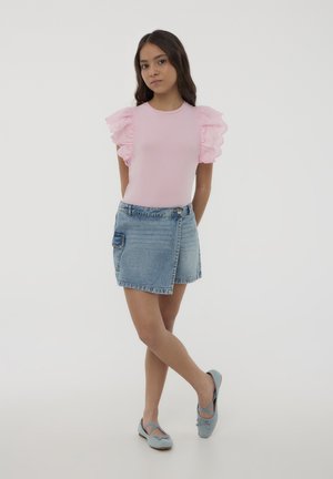 T-shirt in cotone rosa con maniche a rouche in pizzo, abbinato a una gonna di jeans con tasca laterale. Calzature: ballerine azzurro chiaro.