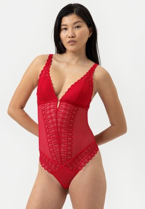 Body en dentelle rouge avec des panneaux en mesh transparent, des bords en scallop, un décolleté en V profond et un zip à l'avant. Design ajusté qui met en valeur la silhouette.