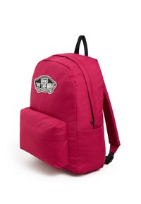 Vaatekaupan vaaleanpunainen Vans-reppu, jossa on pyöreä muoto, edessä tasku, kangasrakennetta ja logopatch. Säädettävät mustat hihnat kantamiseen.