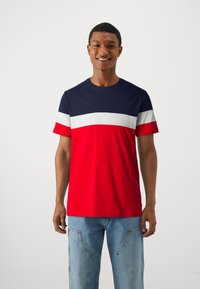 Kortærmet t-shirt i marineblå, hvid og rød; ensfarvede med vandrette striber. Blødt bomuldsstof, crew neck design.