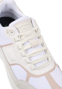 Witte sportieve schoen met een geperforeerd mesh en gladde leren accenten, voorzien van beige details, platte veters en branding op de tong.