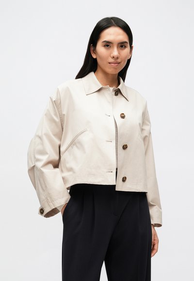 Κοντό μπεζ σακάκι με ανοιχτό γιακά, κούμπωμα με κουμπιά και τσέπη. Υφασμάτινη υφή με λεία επιφάνεια. Μακριά μανίκια με μανσέτες που κλείνουν με κουμπιά.