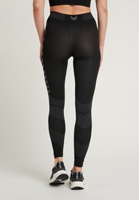 Sorte leggings med høy midje, med en teksturert design, chevronmønstre på de lave bena, og et glatt, elastisk stoff.