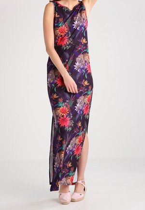 Ærmeløs lang kjole med mørk baggrund, farverigt blomstermønster og leopardprint, sideslids, båret med lyserøde ankelsremssko.