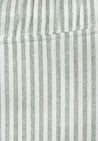 Gestreifte Stoff mit schmalen grünen und weißen Linien, einer weichen Textur und einem subtilen Muster aus kleinen Punkten entlang der Streifen.