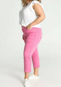 Růžové denimové capri kalhoty s přiléhavým střihem, předními kapsami a pasem na šňůrku. Kombinované s bílým texturovaným topem.