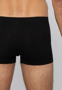 Boxer neri in cotone con una vestibilità aderente, dotati di una texture a costine e di un elastico in vita. Senza etichette o loghi visibili.