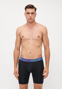 Fekete Nike boxer alsónadrág, lila és zöld mintás derékkal, szoros illeszkedés jellemzi, sima tapintással. További díszítőelemek nincsenek.