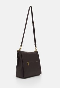 Mørkebrun læder skuldertaske med justerbar rem, hardware i guld-tone og en lille lynlåslomme på forsiden.