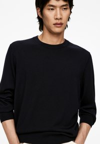 Marineblaues Strickpullover, Rundhalsausschnitt, lange Ärmel mit gerippten Bündchen, weiche Textur, taillierter Schnitt, minimalistisch ohne Muster oder Akzente.