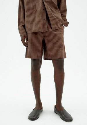 Gestreifte braune Hemd und passende Shorts aus leichtem Stoff. Das Design zeichnet sich durch vertikale Streifen in Dunkelbraun auf einem helleren Braun-Hintergrund aus.