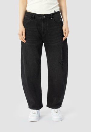 Jeans in denim nero con vestibilità ampia, caratterizzati da un vita alta, dettagli strappati e un design a cinque tasche. Abbinati a sneaker bianche.