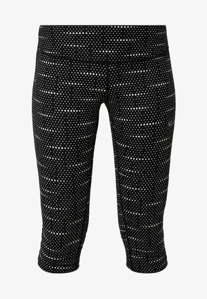 Leggings courts noirs avec un motif à pois blancs uniformément répartis sur le tissu, dotés d'une taille haute.