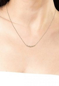 Zilveren ketting met een gebogen ontwerp en zes kleine ronde kralen in goud- en zilvertinten, centraal langs de ketting geplaatst.